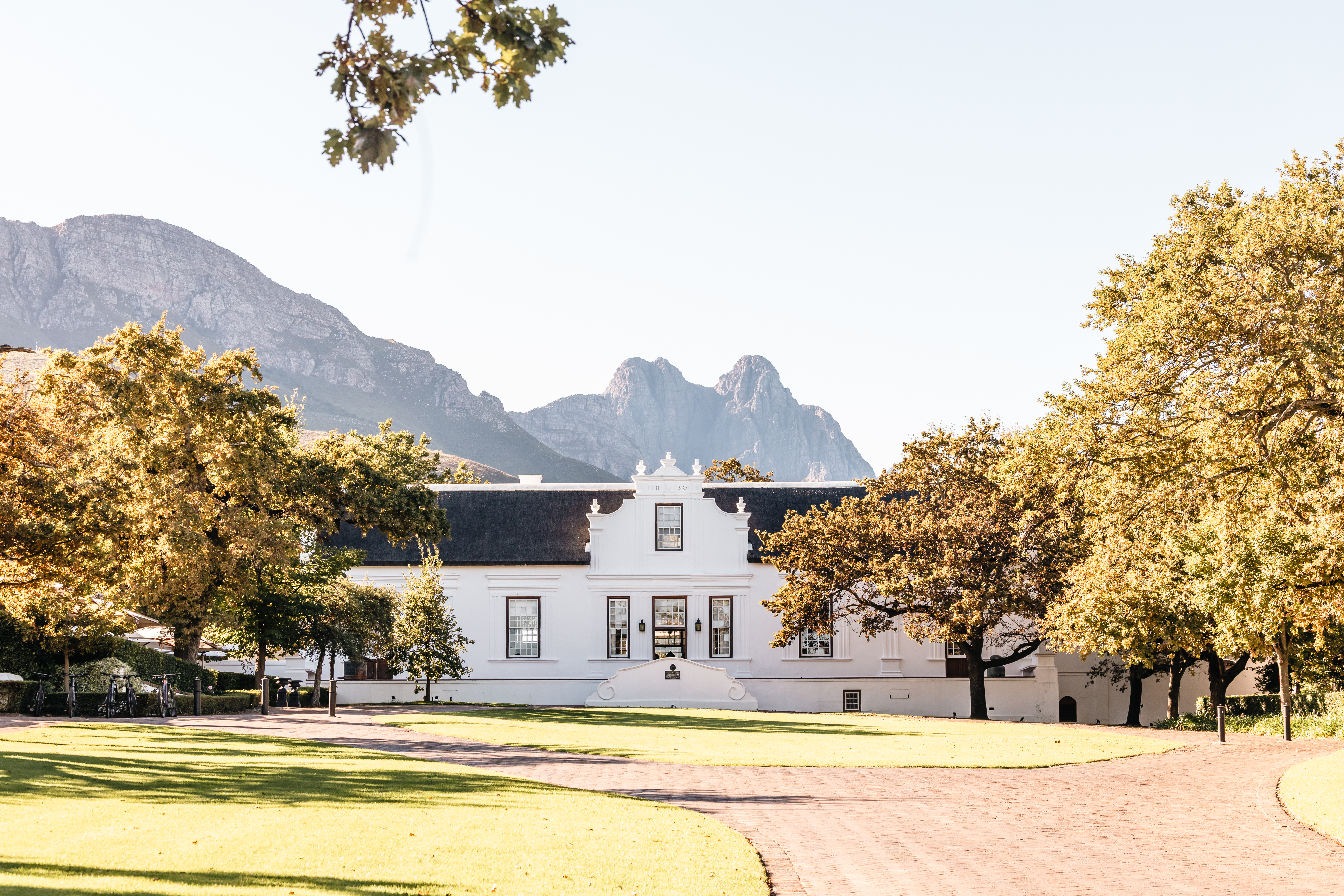 Historic Cape Dutch manor house at Lanzerac with the Jonkershoek Mountains rising behind the estate near Stellenbosch in South Africa’s Cape Winelands.
