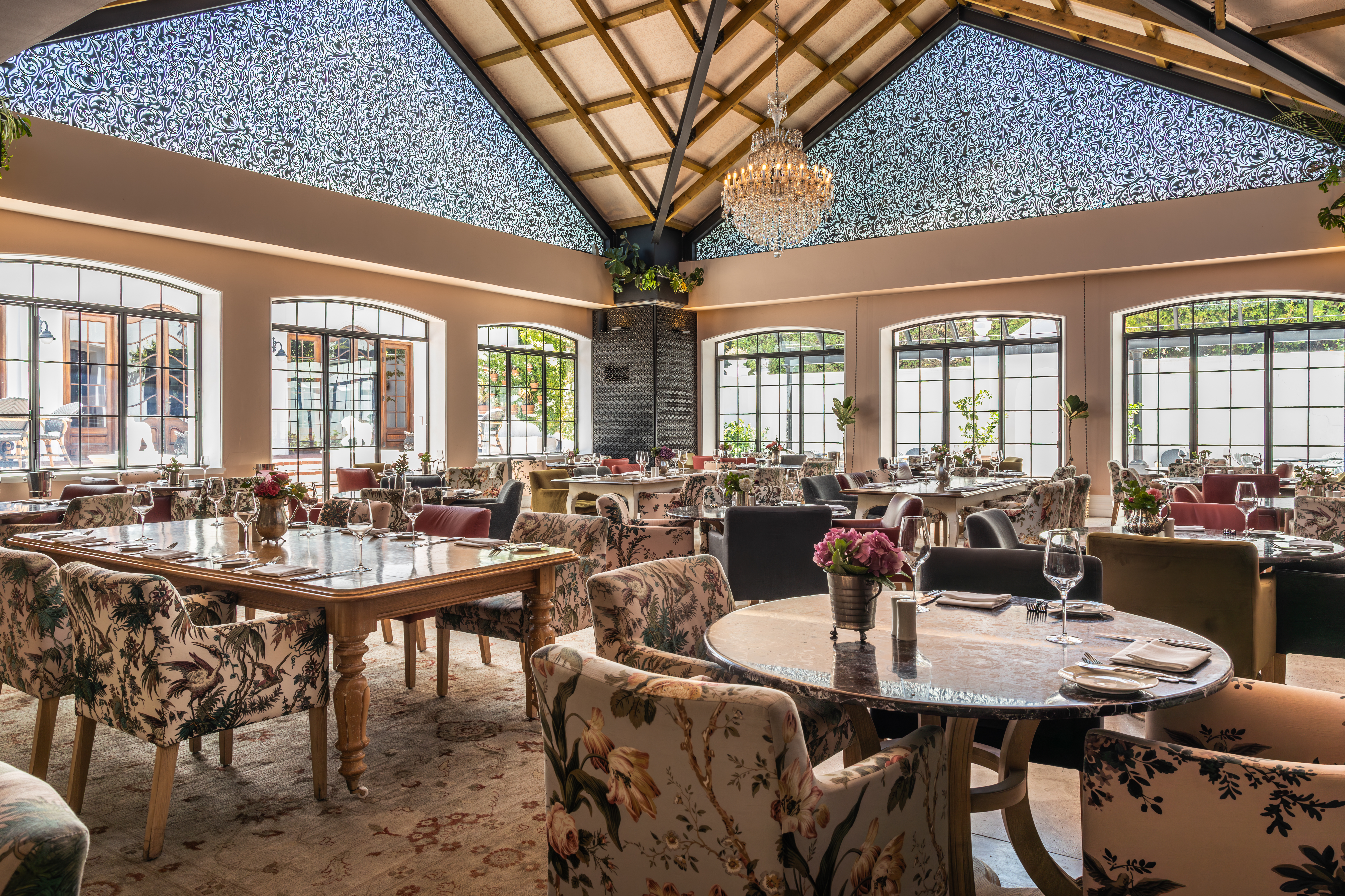Elegant dining room interior at Lanzerac estate in Stellenbosch featuring chandeliers, large windows and tables set for guests in South Africa’s Cape Winelands.