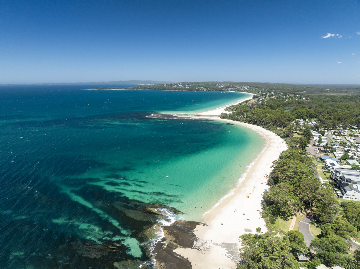Sweeping aerial view across Jervis Bay with turquoise water, white-sand beaches and the coastal communities of Huskisson and Vincentia.