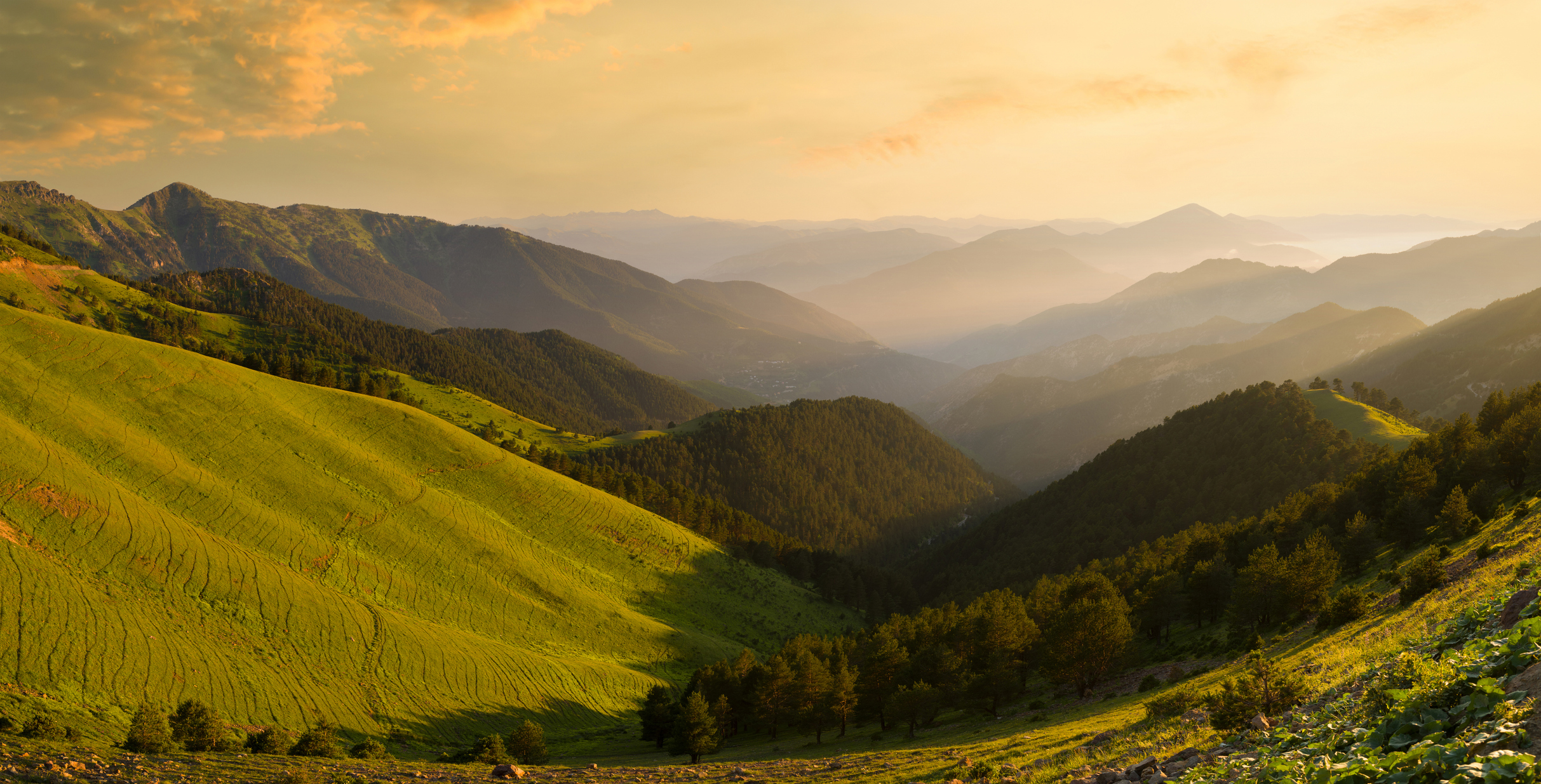 Golden sunset over green mountain slopes and layered ridges of the Zigana Mountains, viewed from Saranoy Plateau in northern Turkey.
