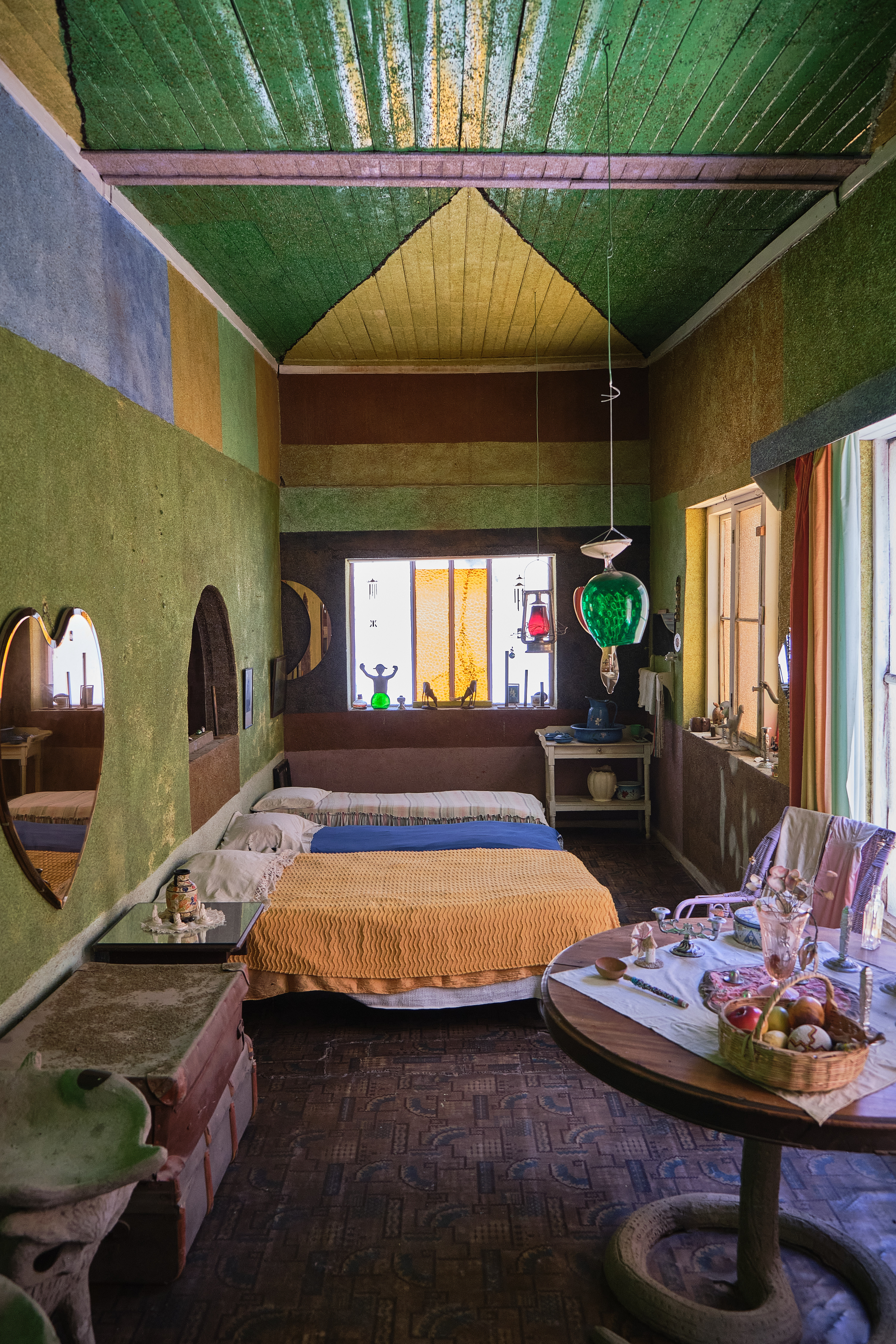 Interior room inside the Owl House in Nieu-Bethesda featuring colourful walls, handmade furnishings and decorative glass elements.