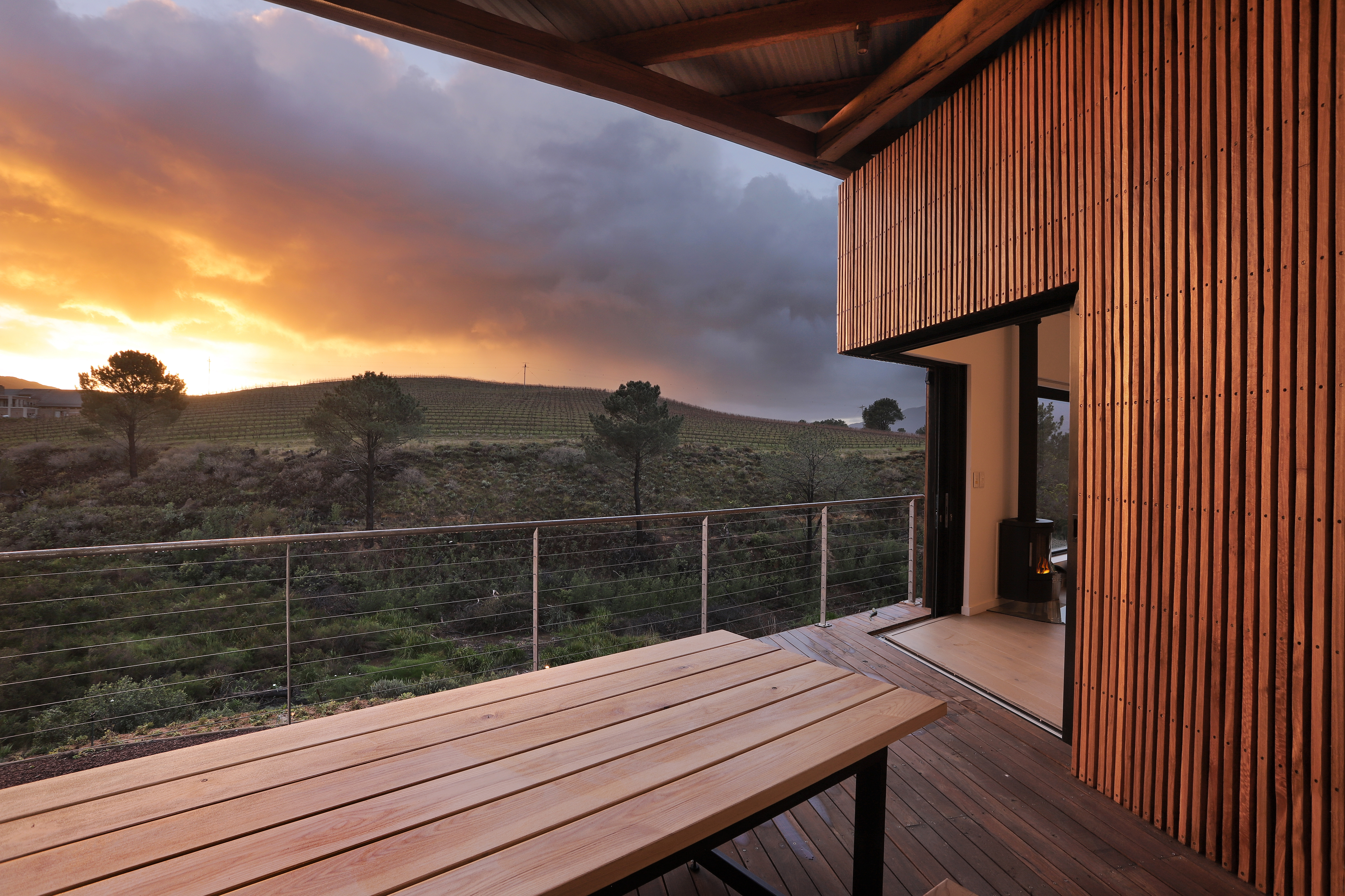 Wood-clad terrace and vineyard lodge at Creation Wines during sunset in the Hemel-en-Aarde Valley, Overberg, South Africa.