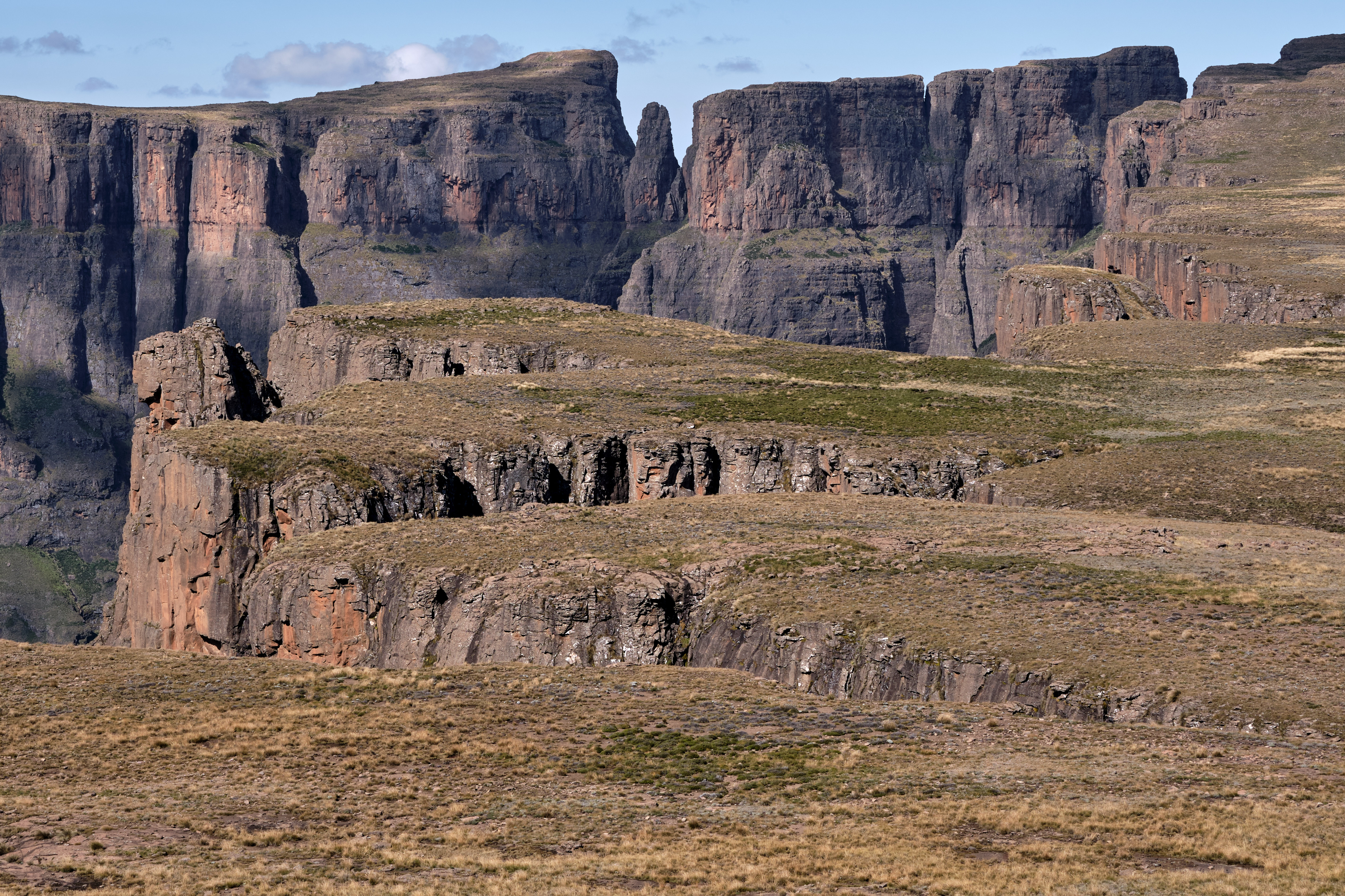 Devil's Tooth rock formation seen from the Drakensberg escarpment, with steep basalt cliffs and high-altitude plateau terrain in the Amphitheatre region.