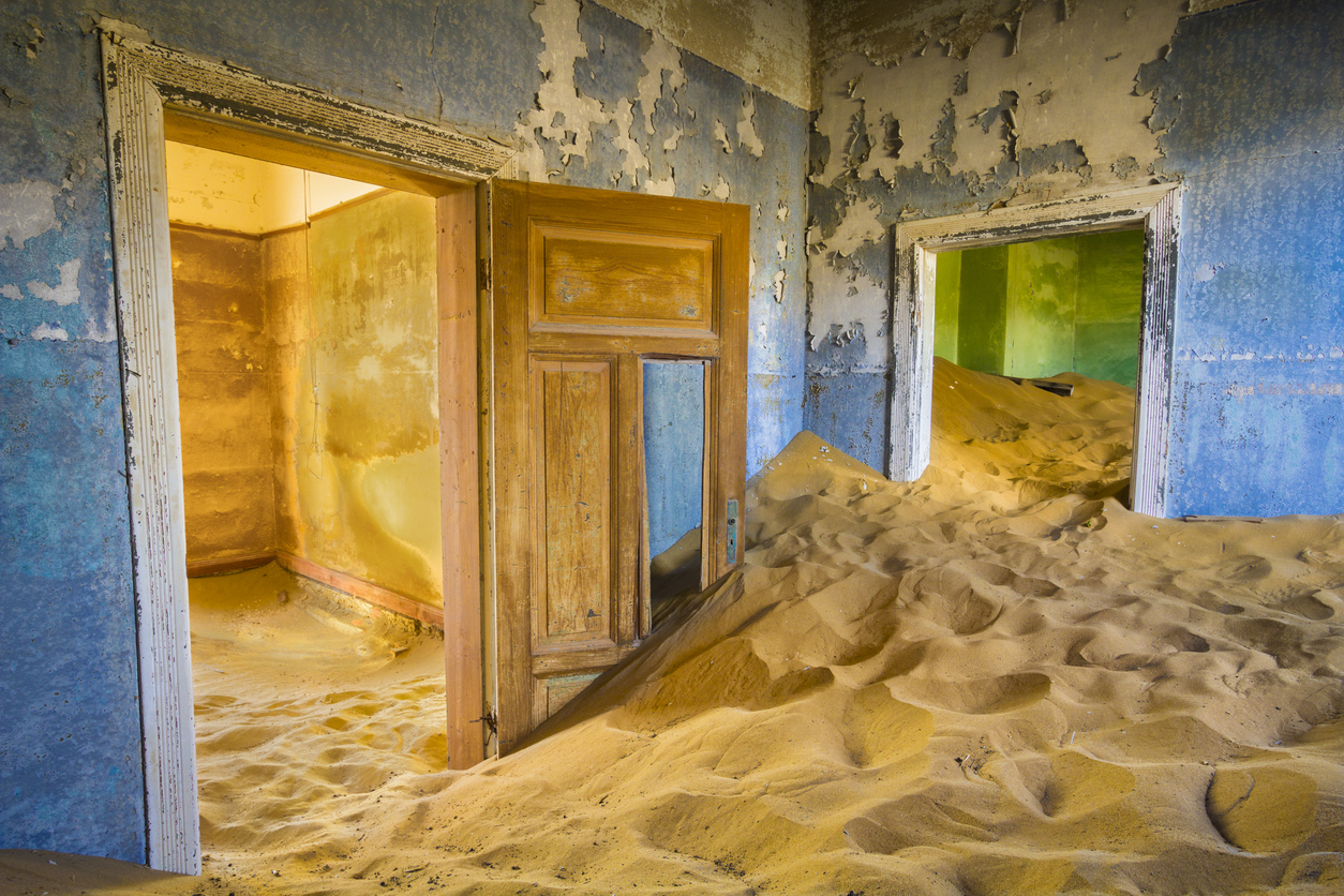 Abandoned interior rooms filled with drifting desert sand in Kolmanskop ghost town, Namibia.