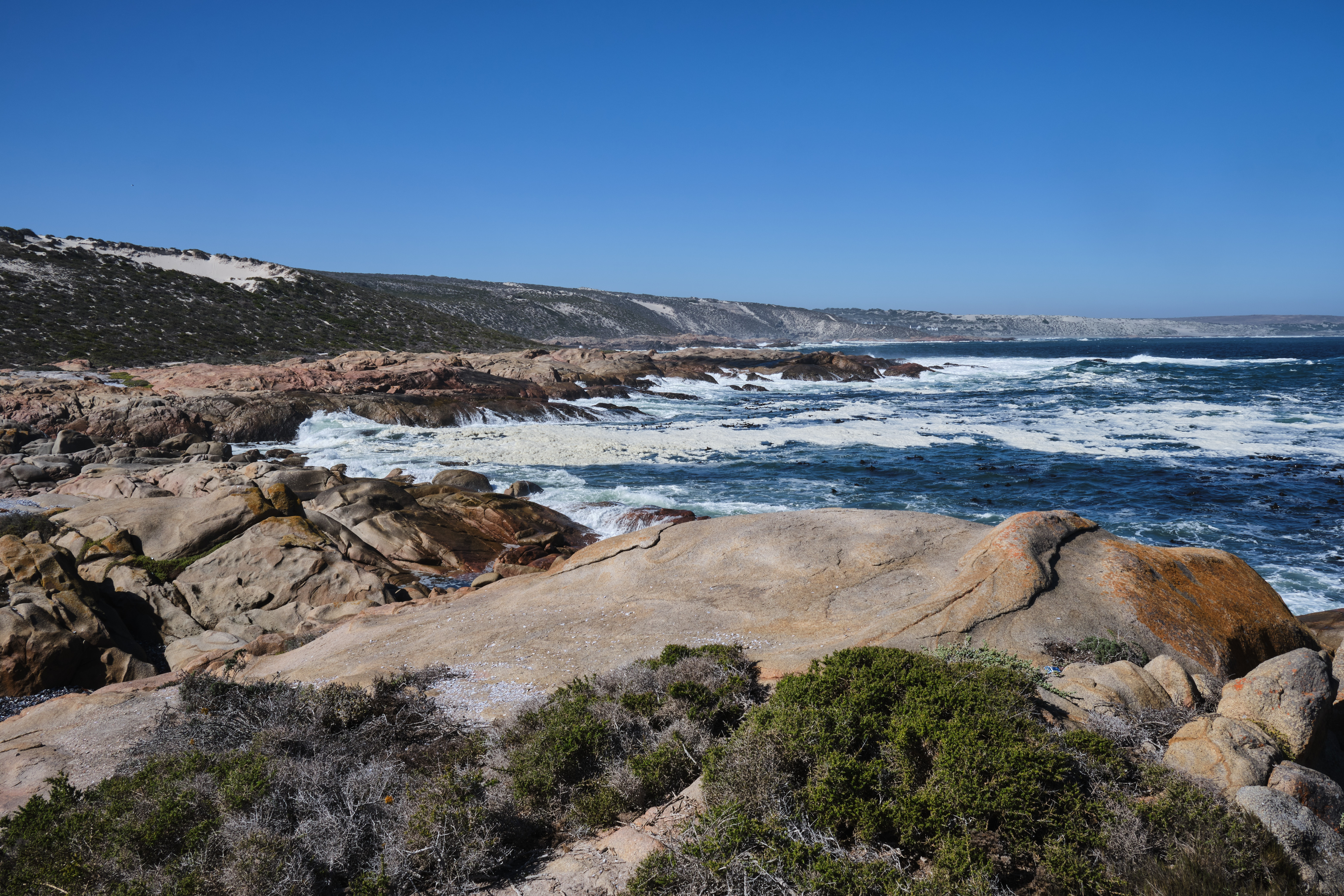 Waves break across smooth granite rock formations along the rugged Atlantic coastline of Cape Columbine Nature Reserve near Tietiesbaai, Western Cape, South Africa.