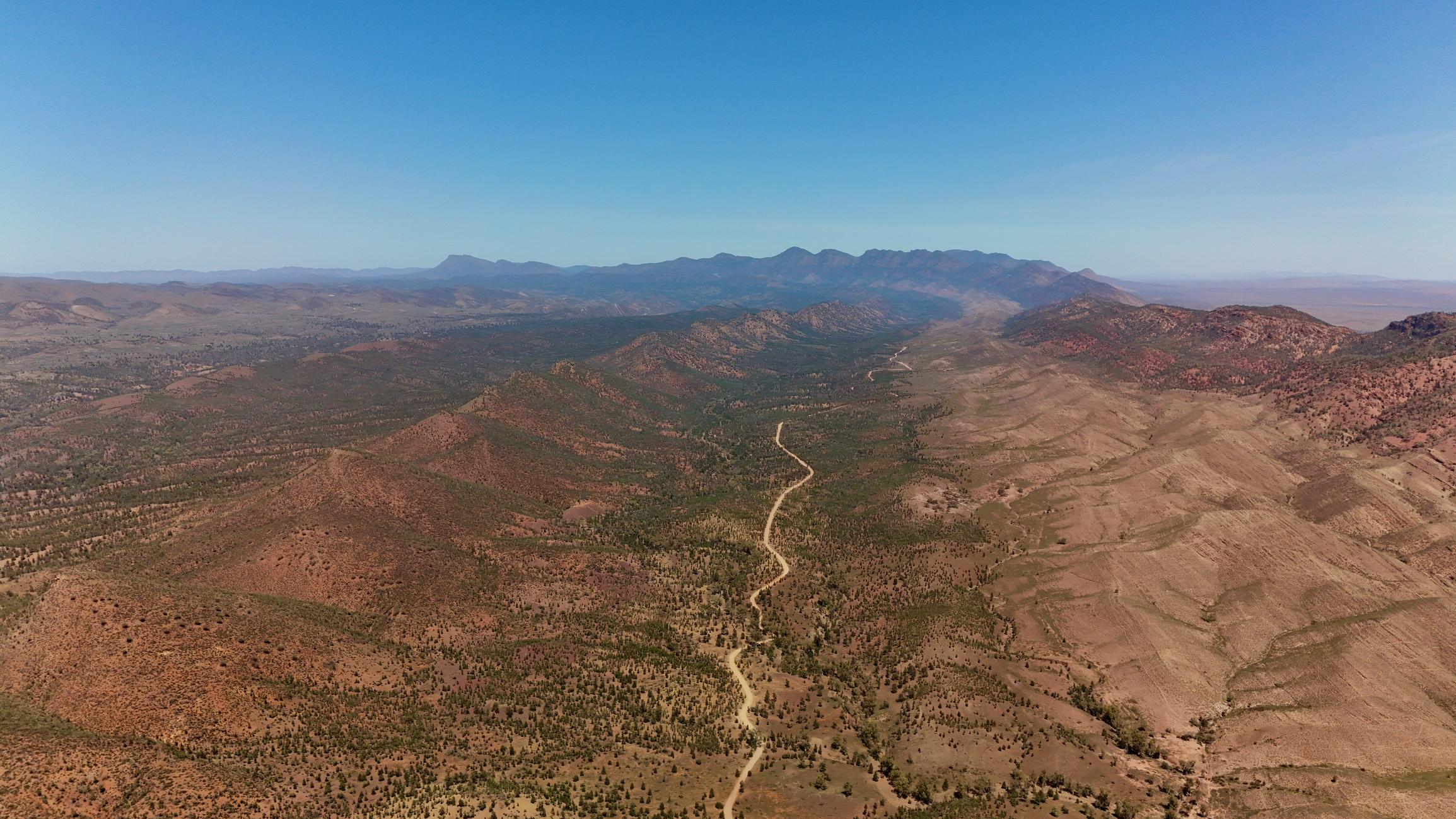Aerial view of Brachina Gorge showing a winding dirt road through rocky outback valleys in the Flinders Ranges, South Australia.