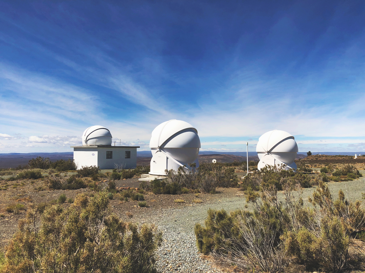 Astronomical telescope domes at the SALT Observatory near Sutherland, surrounded by Karoo shrubland and open skies on the Roggeveld Plateau.