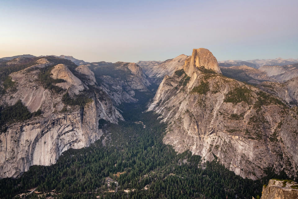 View from Glacier Point in Yosemite National Park showing Half Dome, granite cliffs, and forested Yosemite Valley at dusk.