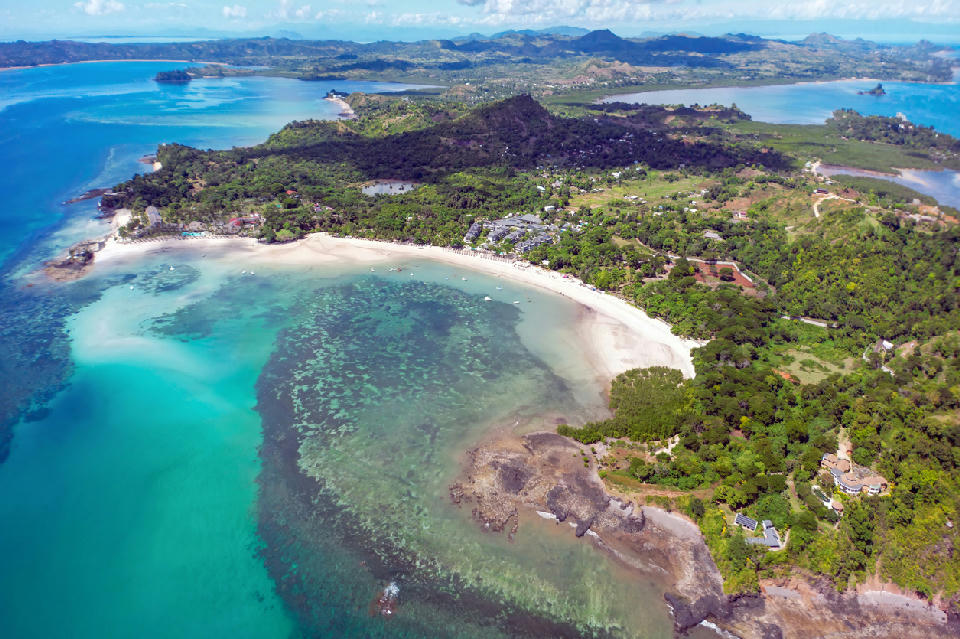Drone view of Nosy Be in Madagascar with Andilana Beach, coral reef formations, turquoise coastal water, and tropical island landscape.