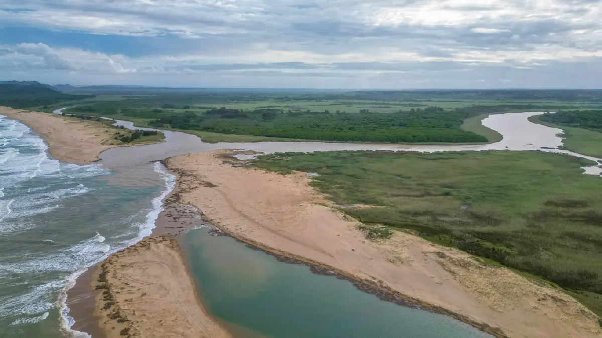 Aerial view of the St Lucia Estuary mouth in iSimangaliso Wetland Park, showing wetlands, sandbanks, winding channels and the Indian Ocean coastline in KwaZulu-Natal, South Africa.