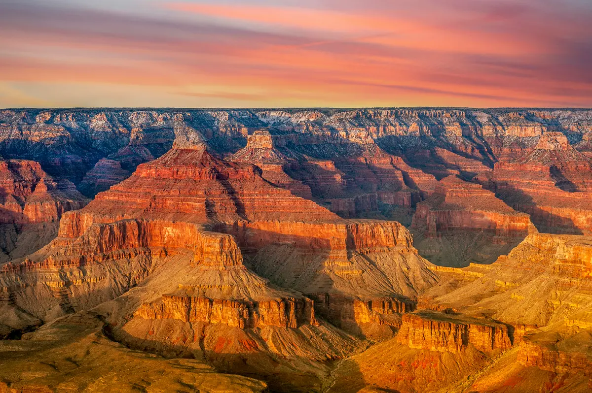 Grand Canyon South Rim at sunset showing layered mesas and buttes with warm light across the canyon landscape
