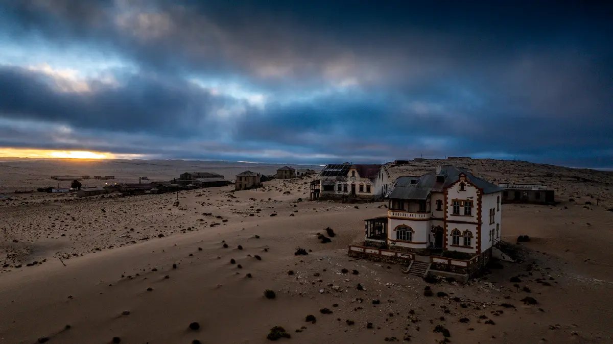 Aerial view of abandoned buildings and desert dunes in Kolmanskop ghost town near Lüderitz, Namibia.