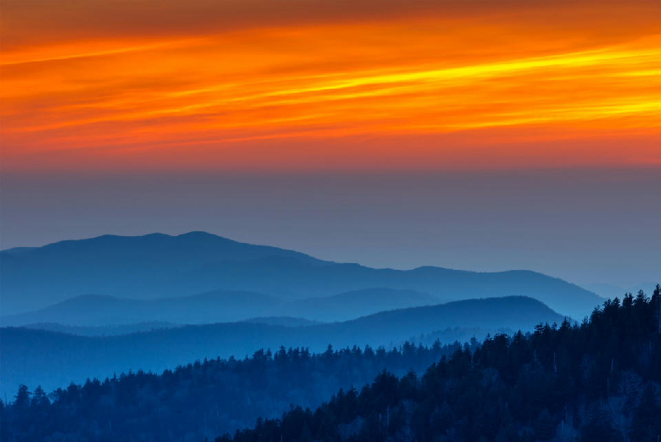 Blue mountain ridges at sunset viewed from Clingmans Dome in Great Smoky Mountains National Park with orange skies and forested foreground layers.