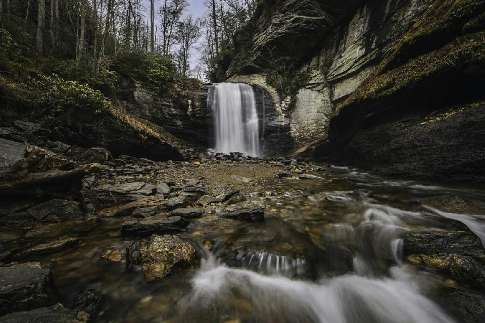 Long exposure photograph of Looking Glass Falls surrounded by layered rock walls and forest in Pisgah National Forest, North Carolina.