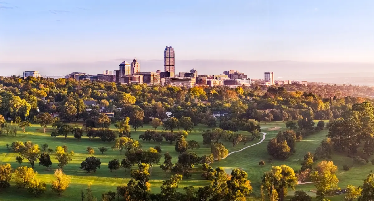 Sunrise view of the Sandton skyline above Wanderers Golf Course and Johannesburg's urban forest in Gauteng, South Africa.