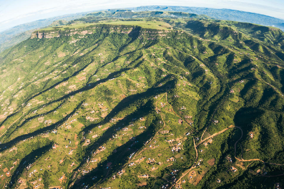 Aerial panorama of the Valley of a Thousand Hills showing green ridges, winding valleys, rural homesteads and layered escarpments stretching across KwaZulu-Natal, South Africa.
