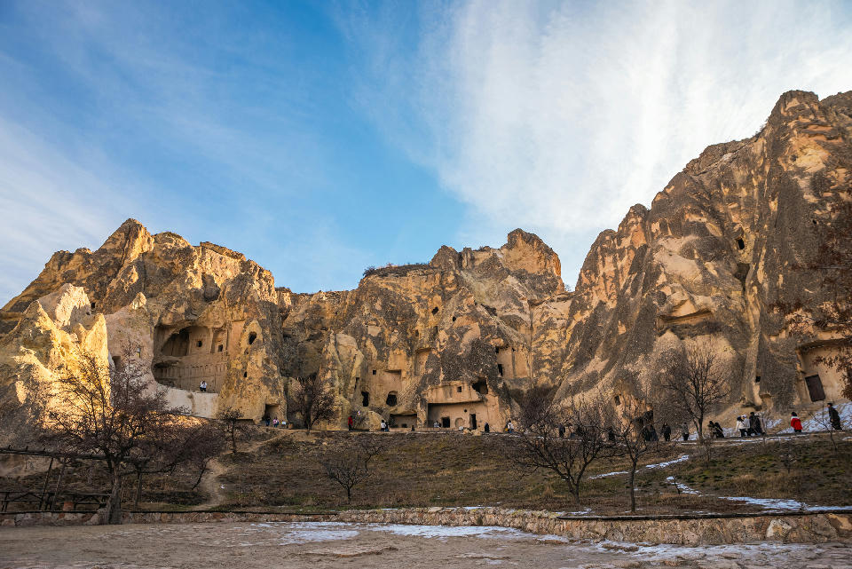 Rock-cut churches and cave monasteries at Göreme Open Air Museum in Cappadocia, Turkey, carved into towering volcanic cliffs beneath a blue sky.