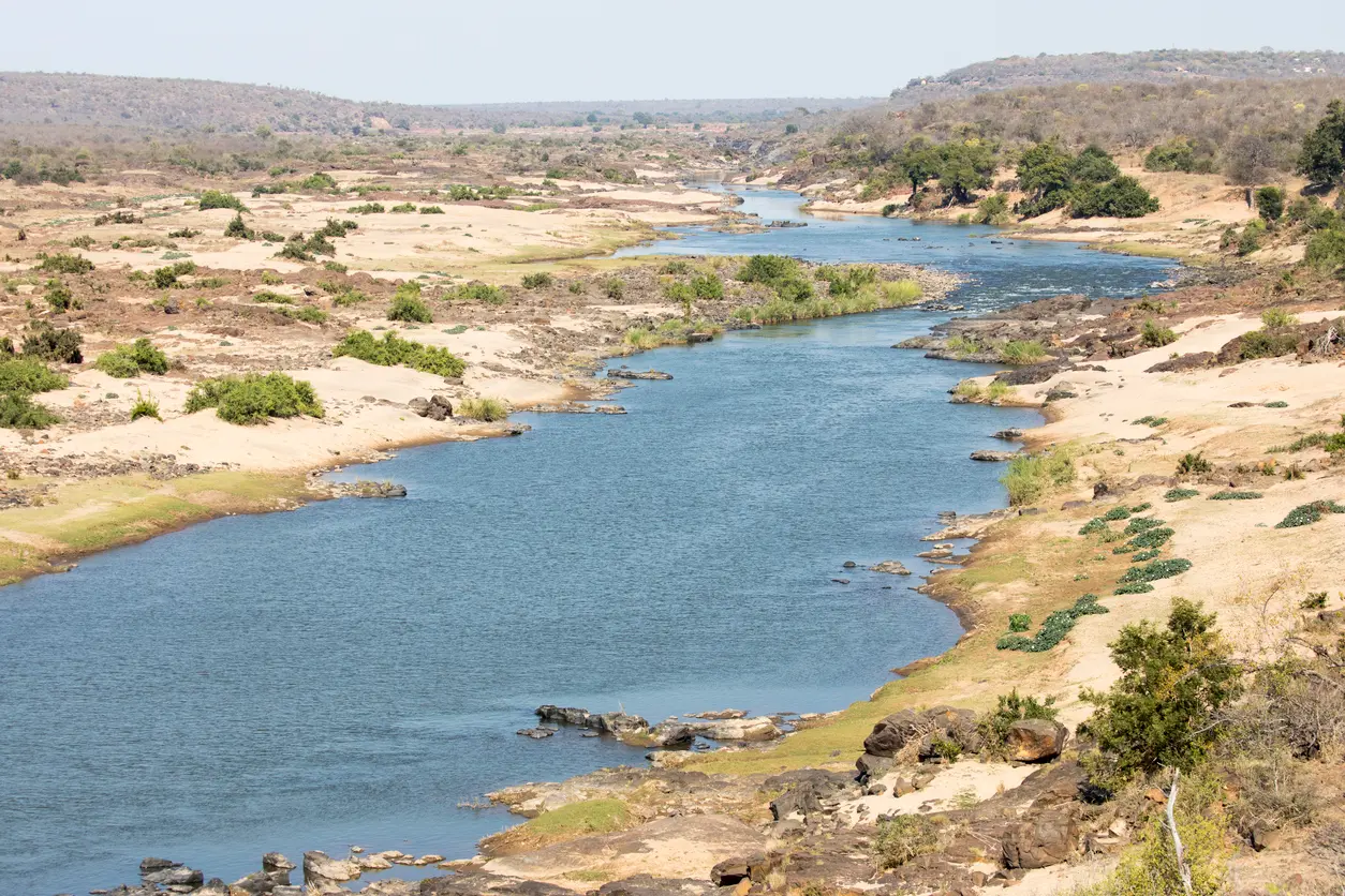 Wide view of the Sabie River flowing through a rocky and sandy valley in Kruger National Park, South Africa.