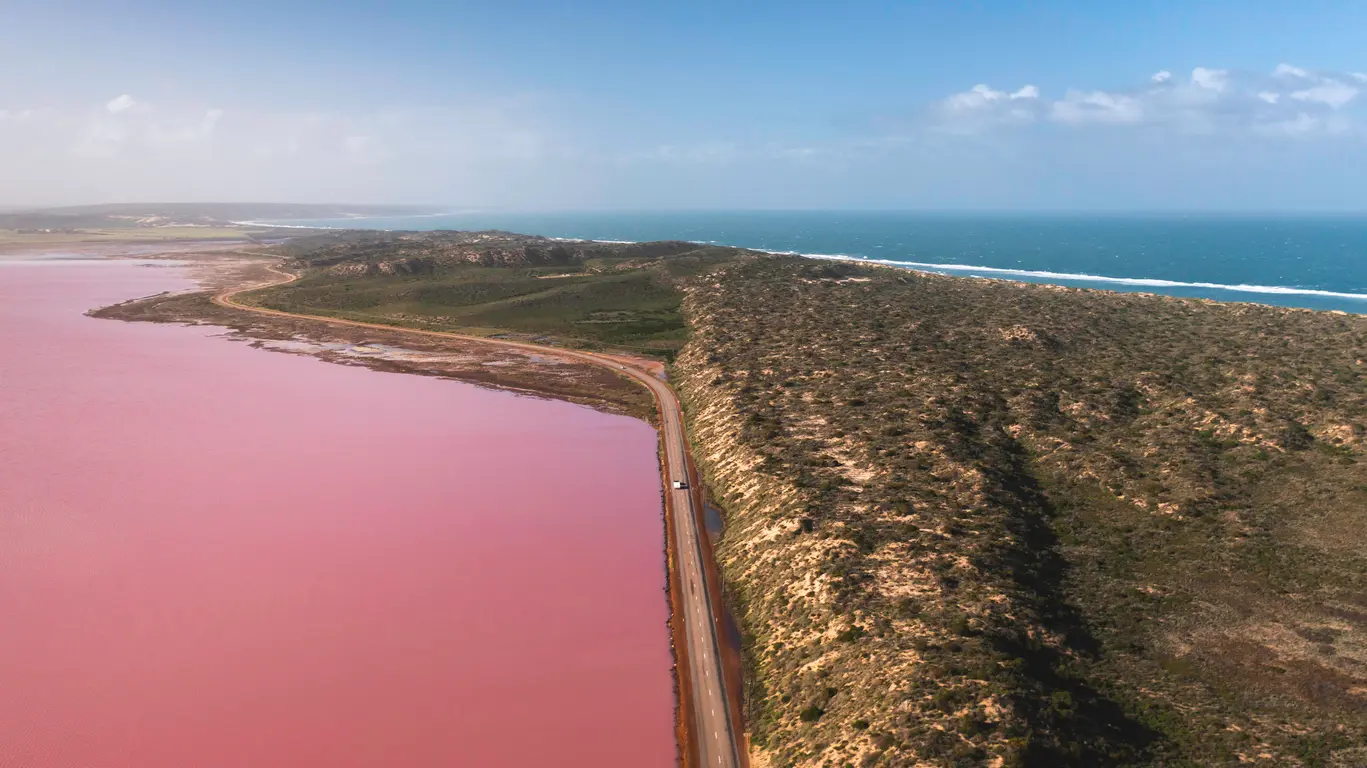 Aerial view of pink Hutt Lagoon beside the coastal road and blue Indian Ocean near Port Gregory.