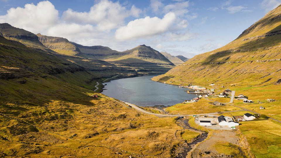 Drone view over Funningsfjørður fjord and small village between steep green hills on Eysturoy, Faroe Islands.