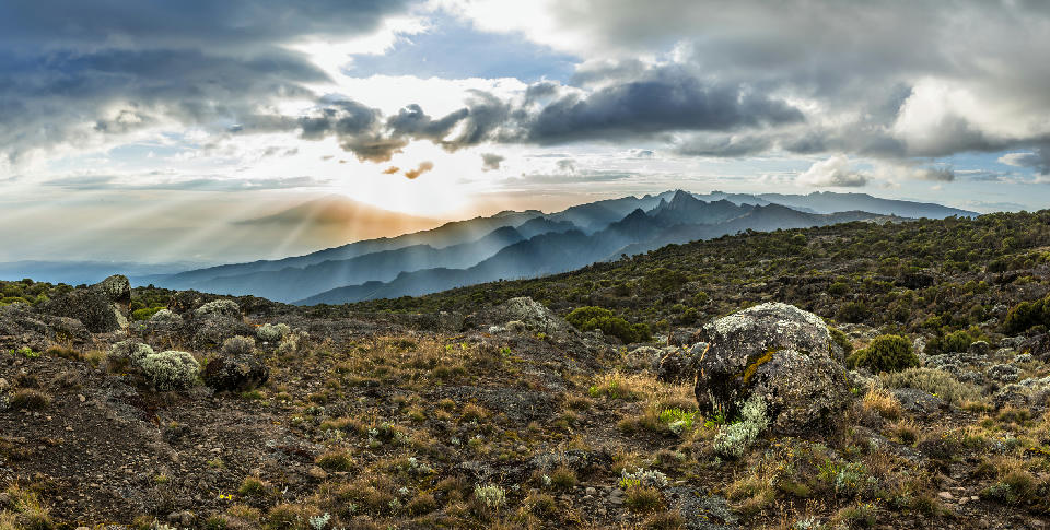 Sun rays breaking through dramatic clouds above Mount Meru, viewed from the Shira Plateau on Mount Kilimanjaro, Tanzania, at an altitude of approximately 3,800 metres above sea level.