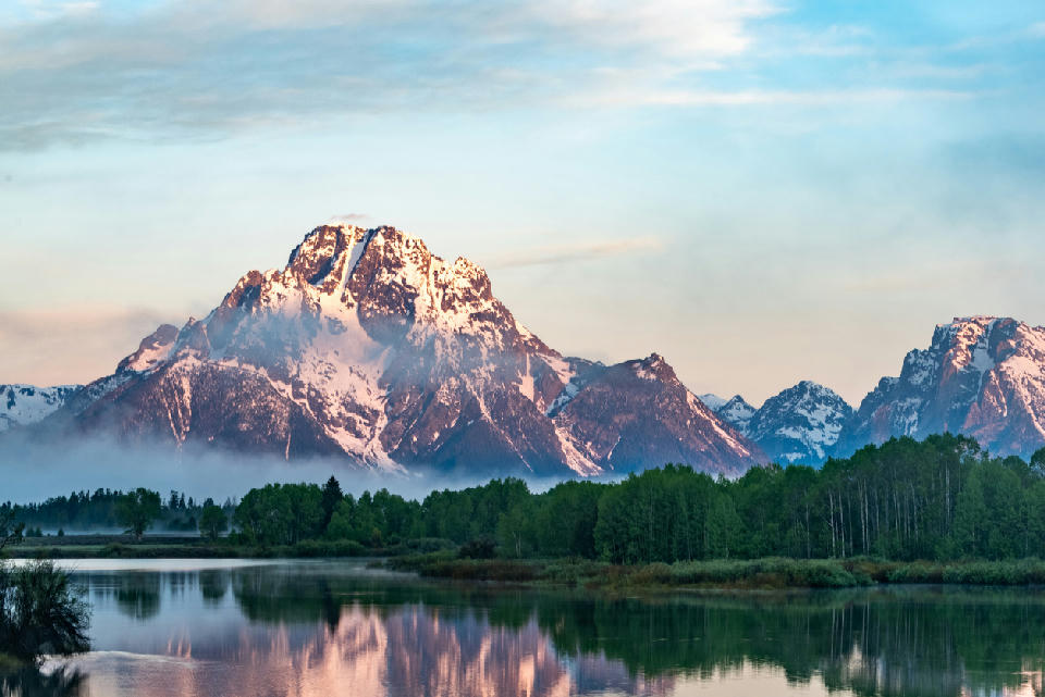Mount Moran reflected in the Snake River at Oxbow Bend with soft sunrise light and low mist, Grand Teton National Park, Wyoming.