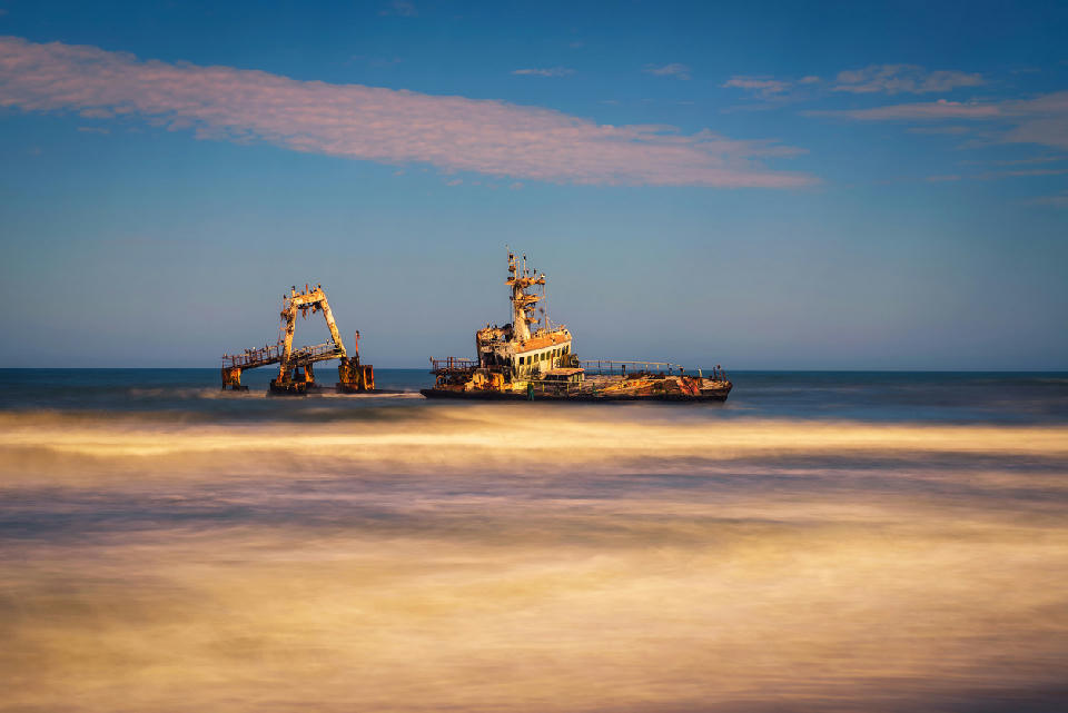 Long-exposure view of the abandoned Zeila shipwreck off Namibia’s Skeleton Coast with waves blurred around the rusting vessel.