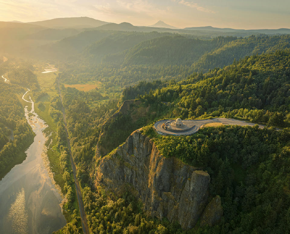 Vista House at Crown Point in the Columbia River Gorge, Oregon USA, with aerial view of cliffs, river valley, and forest at golden hour.