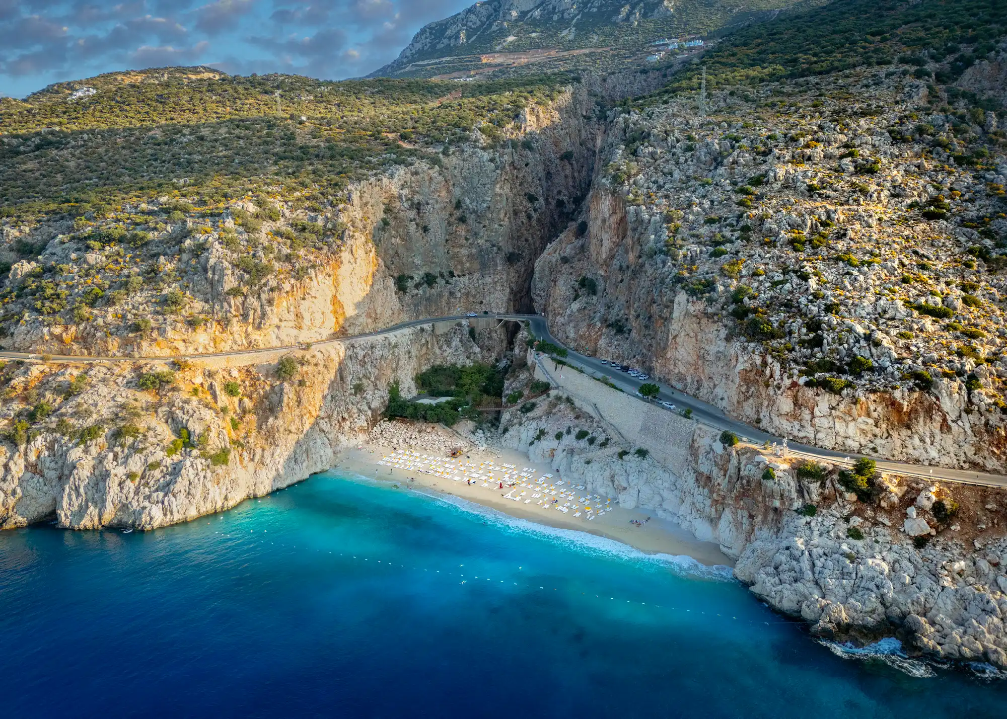 Aerial view of Kaputaş Beach, with turquoise Mediterranean water, steep rocky cliffs and the coastal road between Kaş and Kalkan, Turkey.