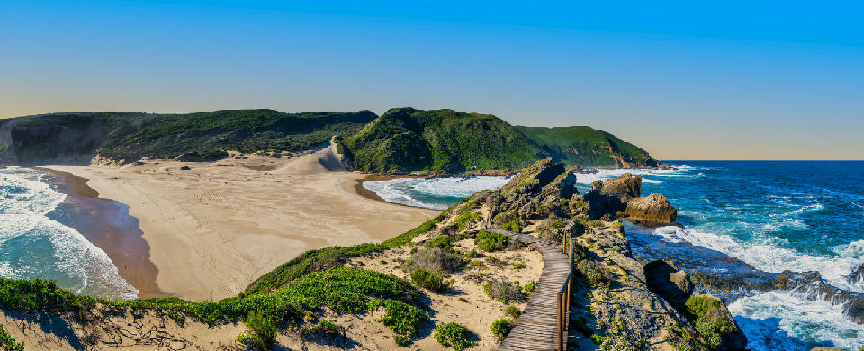 Boardwalk on Robberg Peninsula overlooking sandy beaches, rocky cliffs and turquoise ocean waters near Plettenberg Bay, South Africa.