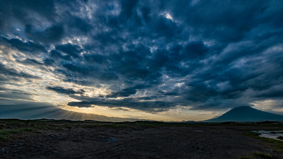 Dark storm clouds illuminated by sunrise over Ol Doinyo Lengai volcano and the Great Rift Valley near Lake Natron in northern Tanzania.