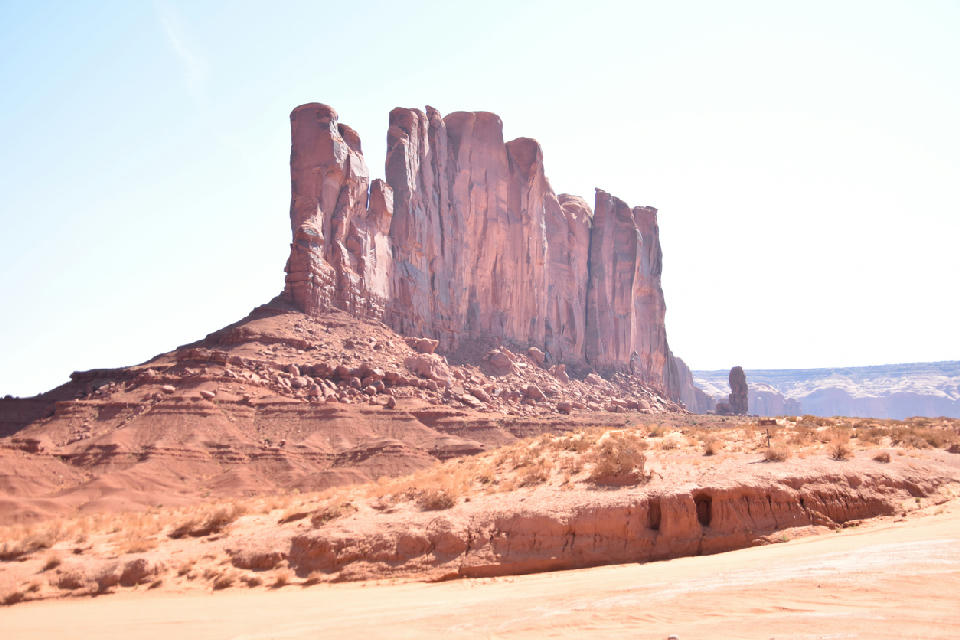 West Mitten Butte in Monument Valley showing a tall isolated sandstone formation rising from a flat desert plain in Utah Arizona.