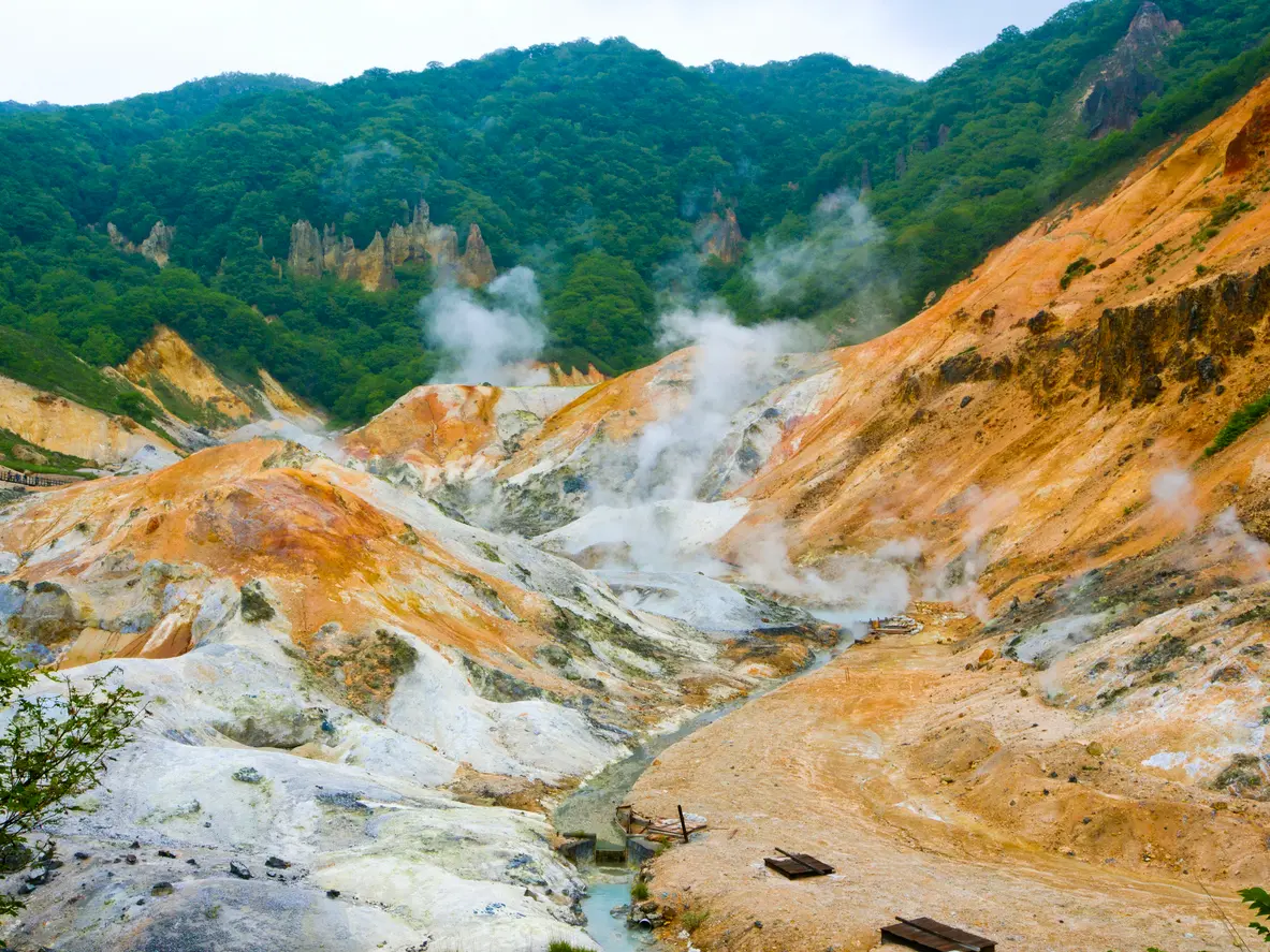 Steam rising from sulphur-coloured geothermal slopes in Jigokudani Hell Valley, Noboribetsu, Hokkaido, Japan.