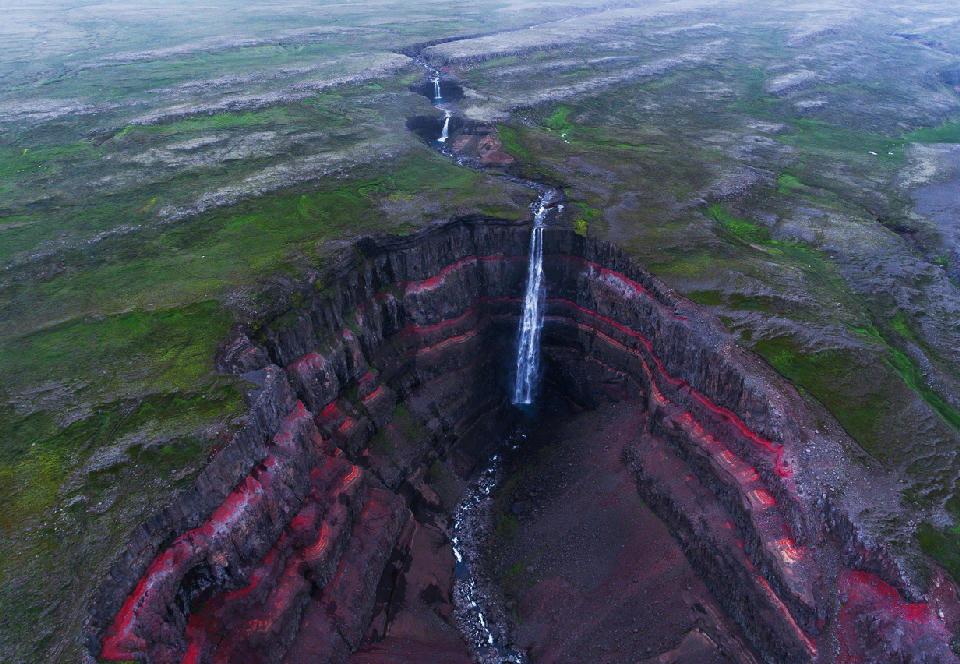Hengifoss waterfall dropping into a layered red basalt canyon in the Eastfjords, eastern Iceland.