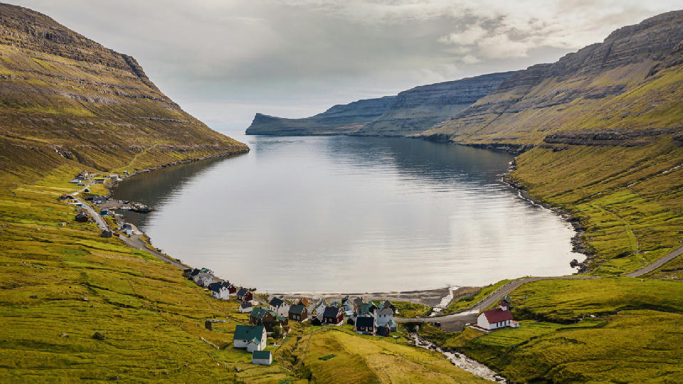 View across Árnafjørður fjord and natural harbour on Borðoy Island, Faroe Islands, under a cloudy sky.
