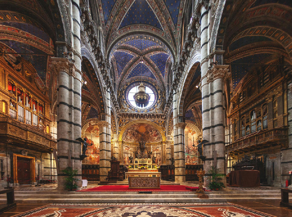 Interior of Siena Cathedral (Duomo di Siena) showing the nave, altar and richly decorated vaulted ceiling in Siena, Tuscany, Italy.