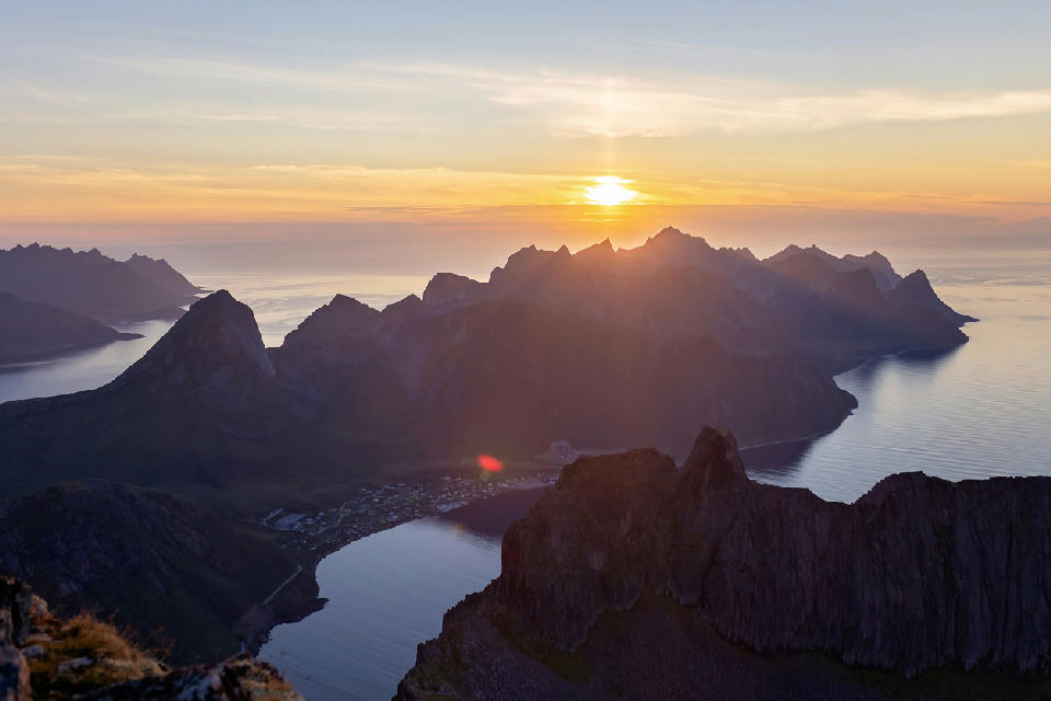 Grytetippen Senja Norway sunset view over fjords and rugged mountain ridges with coastal village below and open sea beyond.