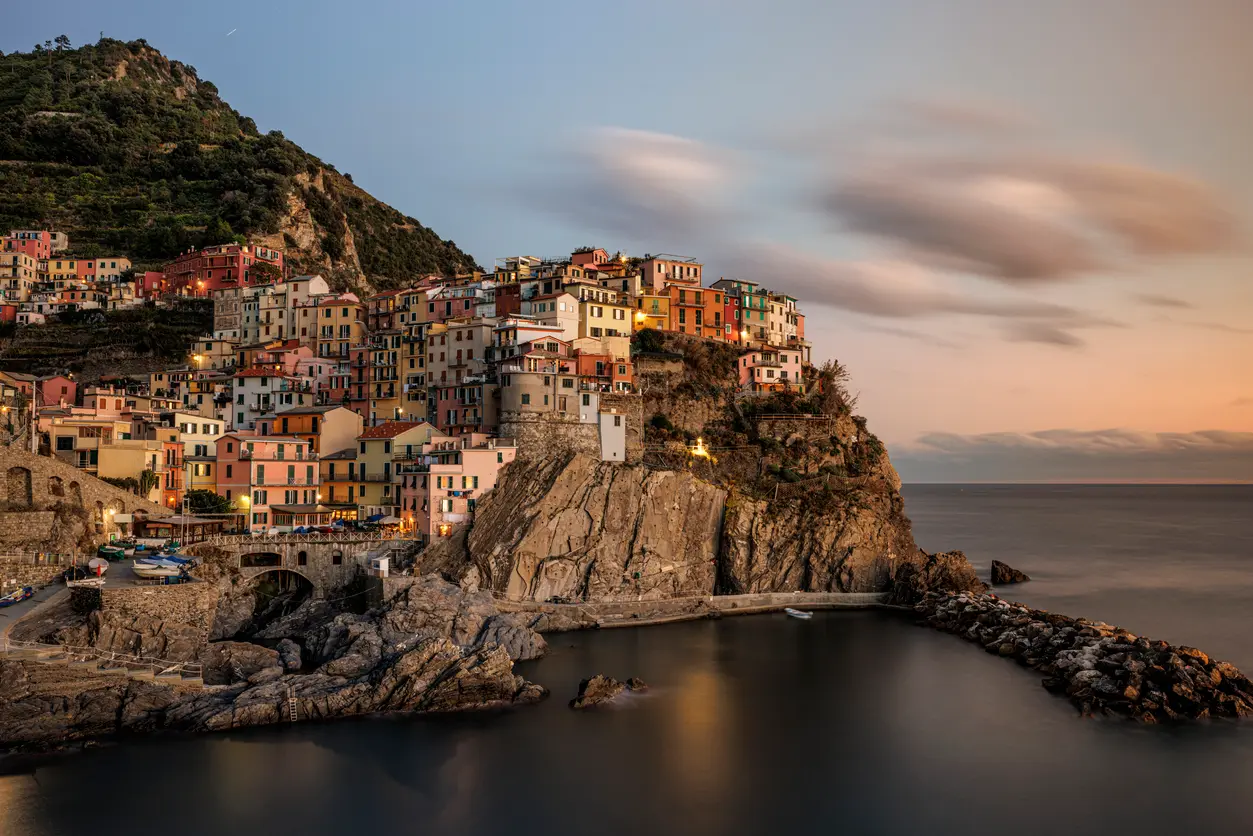 Long exposure sunset view of Manarola, with colourful houses above the sea in Cinque Terre, Italy.