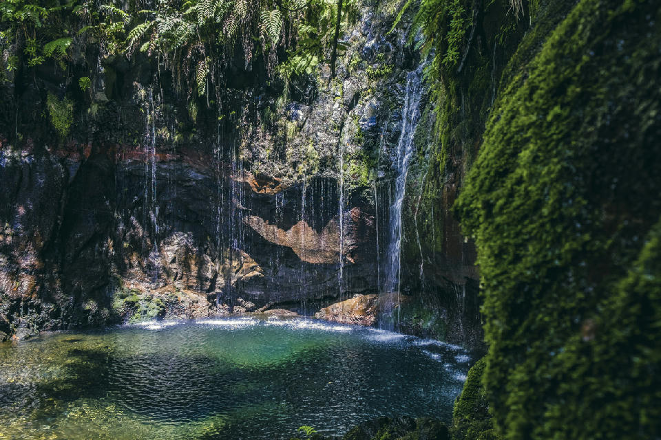 Small waterfalls flowing into a green pool at 25 Fontes in the Rabaçal valley on Madeira Island.