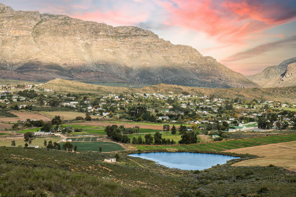 Landscape view of Barrydale surrounded by agricultural fields and mountain ridges at sunset along Route 62 in the Western Cape, South Africa.