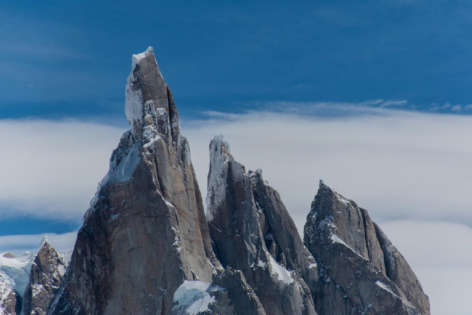Detailed view of Cerro Torre peaks with snow-covered granite spires against a blue sky in Patagonia, Argentina.