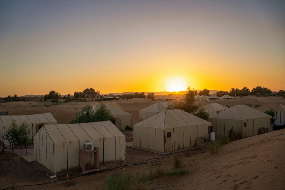 Luxury glamping camp at sunset in the Erg Chebbi dunes near Merzouga, Morocco.