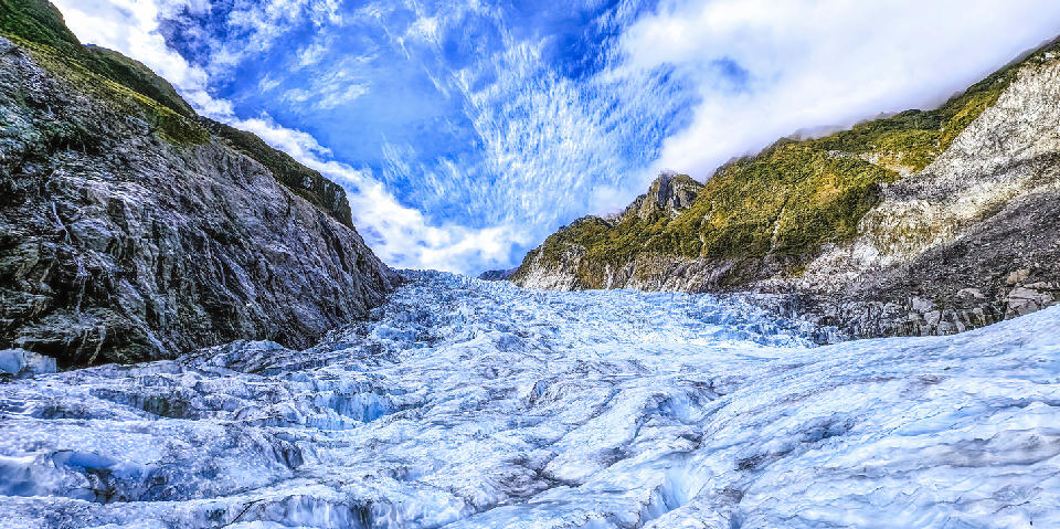 Fox Glacier descending between steep rock walls in Westland Tai Poutini National Park, South Island, New Zealand.