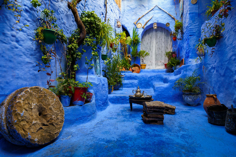 Blue-painted courtyard and staircase leading to a traditional arched doorway in Chefchaouen, Morocco