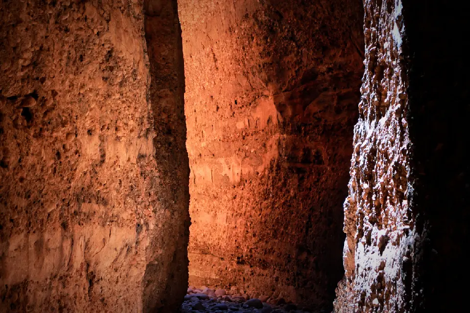 Sunlight penetrates the narrow walls of Echidna Chasm, creating a vivid orange glow on the towering sandstone cliffs.