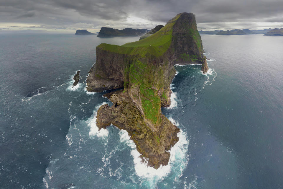Aerial view of steep green cliffs and narrow ridge on Kalsoy Island surrounded by the North Atlantic in the Northern Islands of the Faroe Islands.