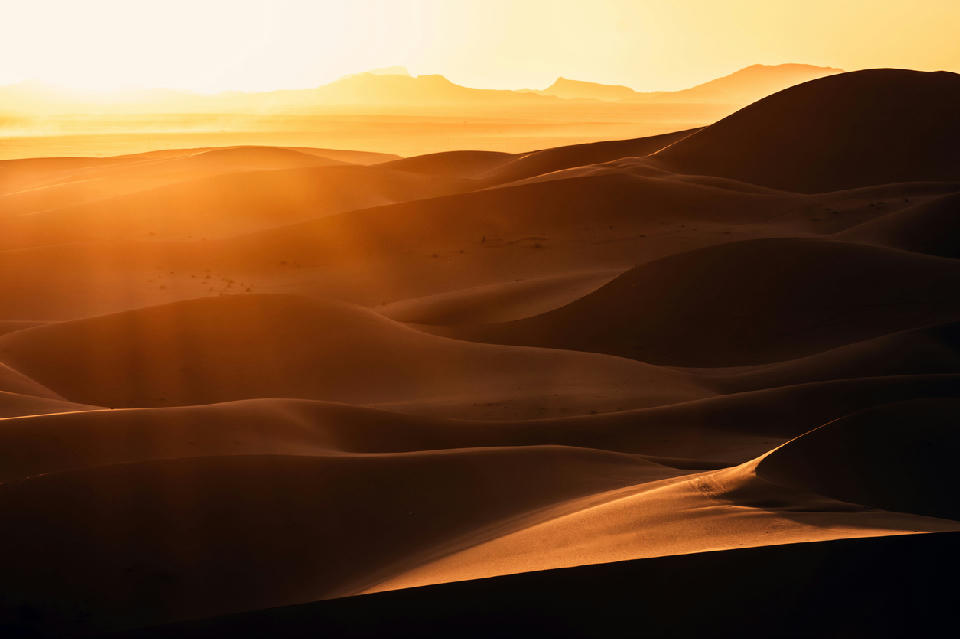 Sunrise light over layered sand dunes in the Erg Chebbi desert near Merzouga, Morocco.