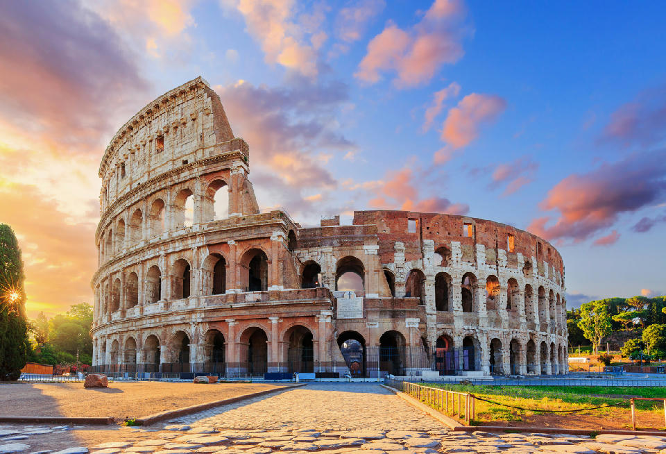 Sunrise view of the Colosseum in Rome, with early light illuminating the historic stone structure.