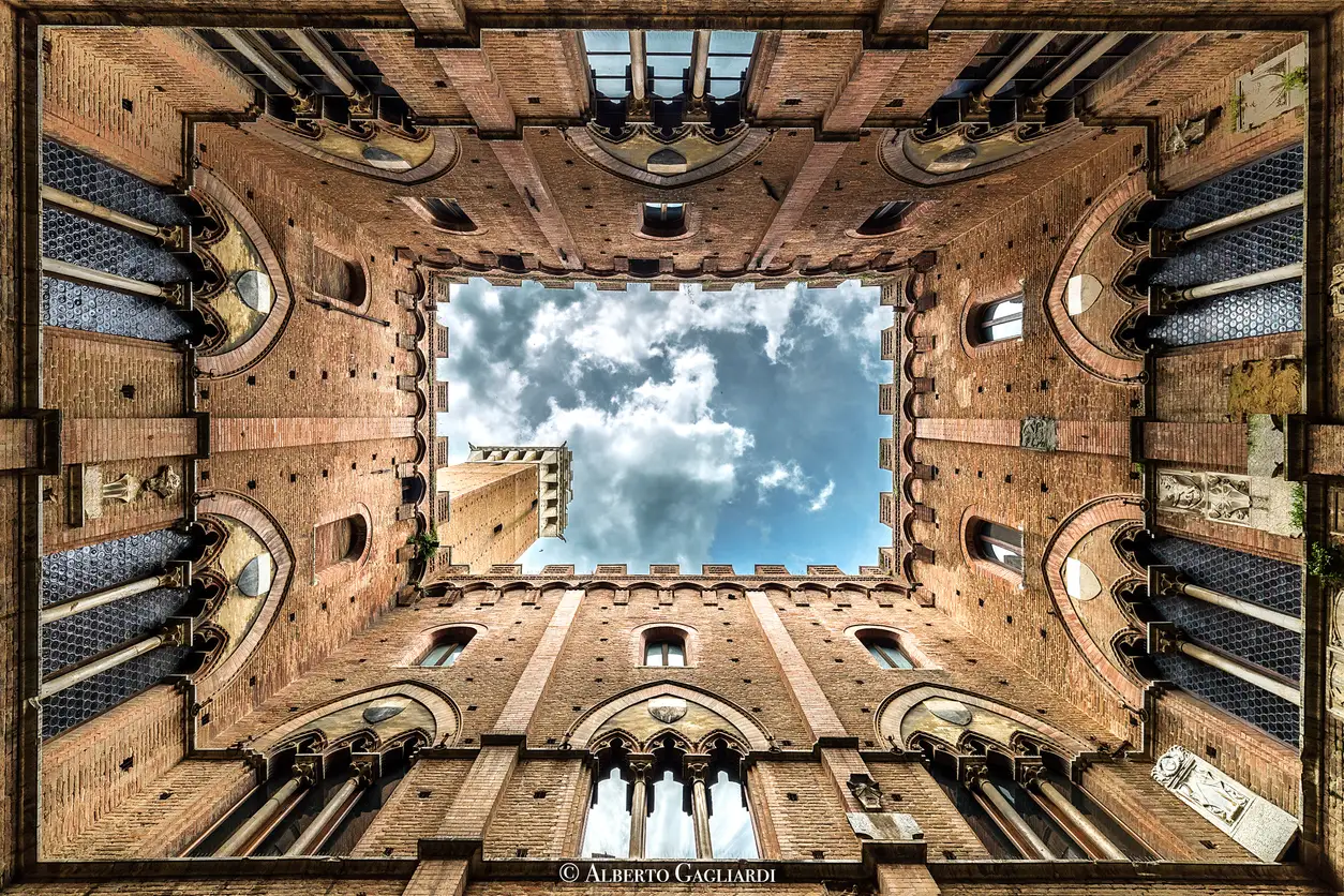 Looking up from the courtyard of Palazzo Pubblico toward the Torre del Mangia in Siena, Tuscany, Italy.