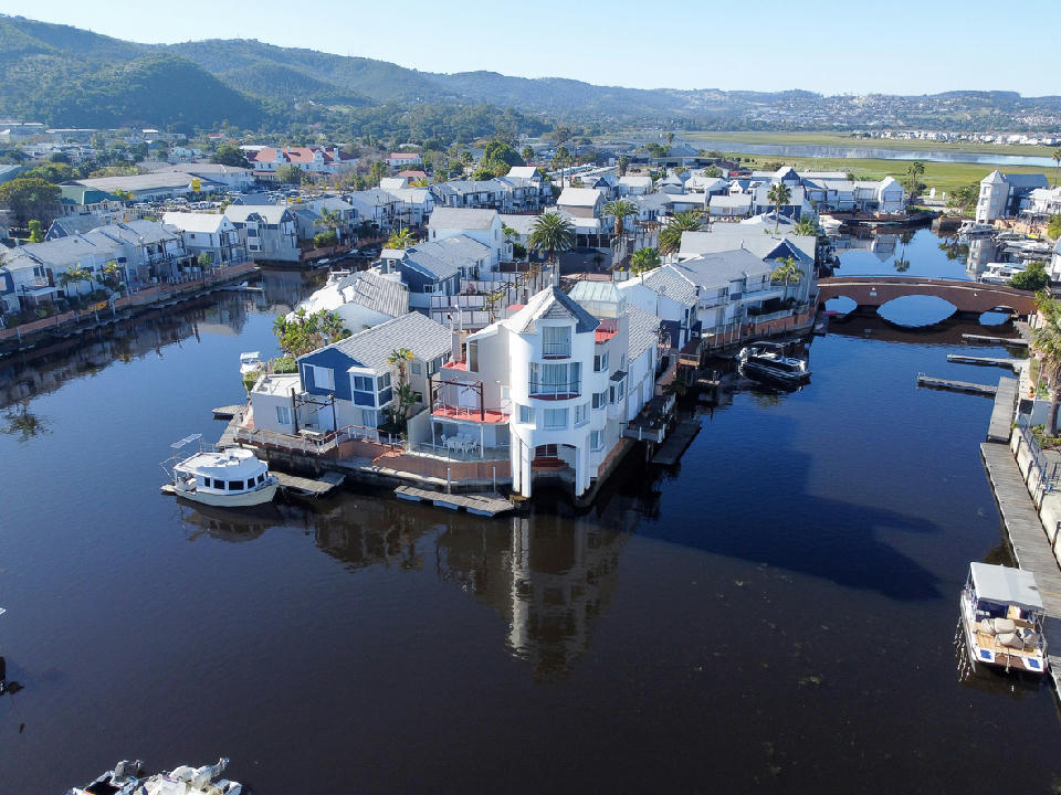 Aerial view of Thesen Island with waterfront houses, canals, private docks, boats and a pedestrian bridge in Knysna Lagoon, South Africa.
